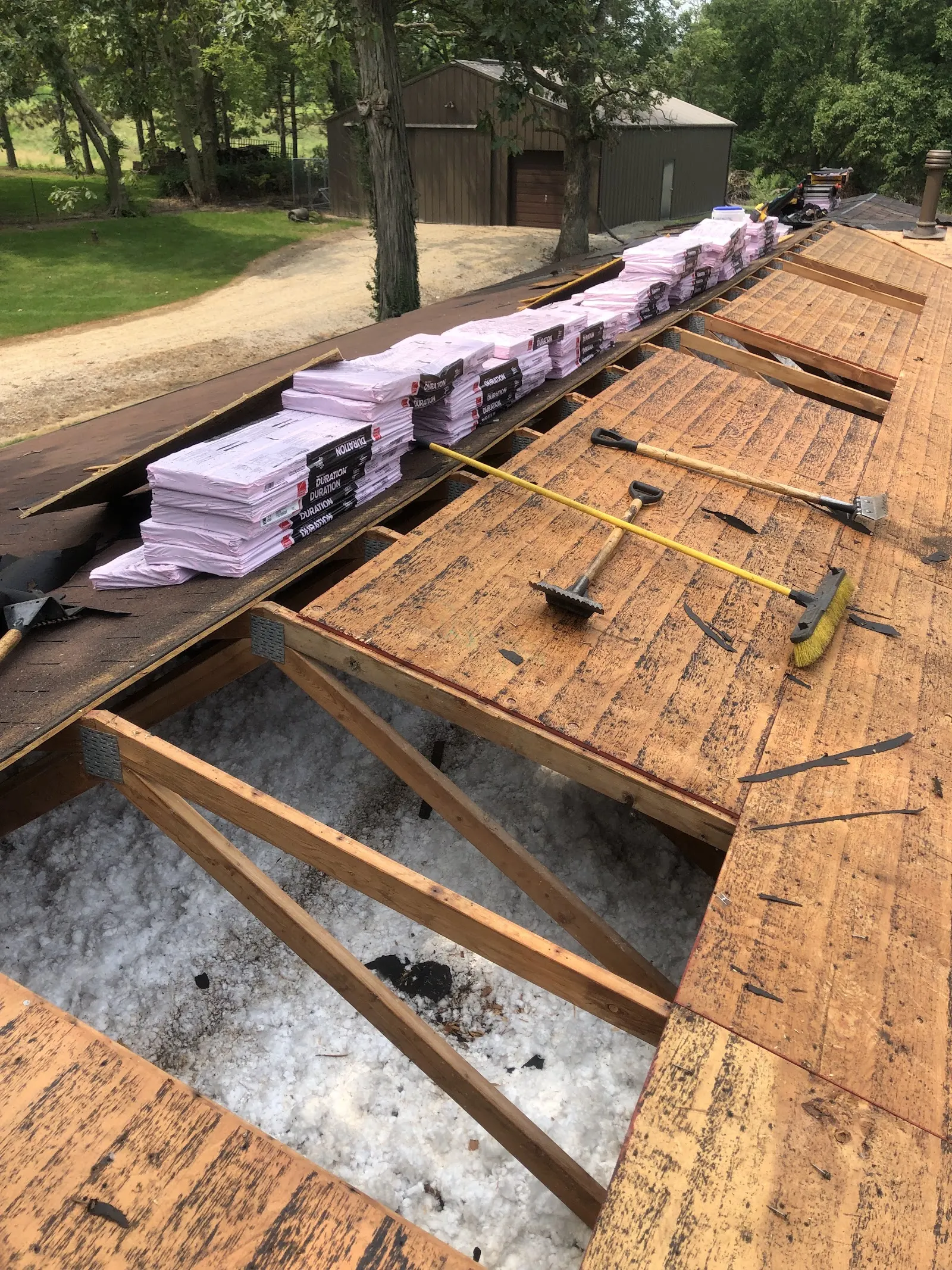 Tear-off with new shingles staged on the decking